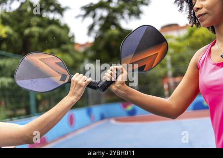 Zugeschnittenes Nahfoto von Frauen aus verschiedenen Rassen, die vor dem gemeinsamen Spiel gegen Pickelball-Schläger kämpfen Stockfoto