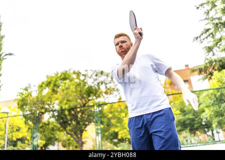 Porträt mit niedriger Blickwinkel und Bewegung eines energischen kaukasiers, der auf einem Platz im Freien Pickelball spielt Stockfoto