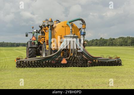 Landwirtschaft, Einspritzen von Gülle mit Traktor und Gelbgeier-Streuwagen Stockfoto