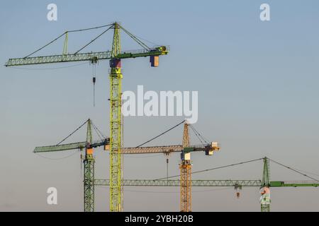 Vier bunte hohe turmdrehkrane im Abendlicht an einem sommerlichen Abend Stockfoto