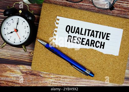 Qualitativer Forschungstext auf gerissenem Papier mit Wecker von oben geschrieben Stockfoto