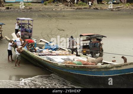 Männer laden Vorräte von einem Boot auf die Sandküste von Bahía Málaga, Kolumbien. Die Waren werden in ein Kleinfahrzeug für den Vertrieb im Inland überführt. Stockfoto