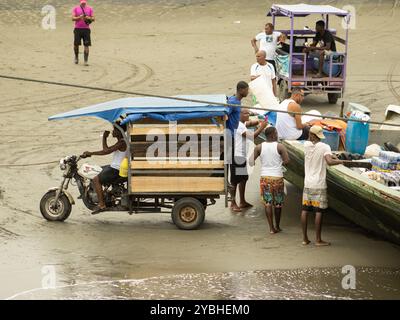 Männer laden Vorräte von einem Boot auf die Sandküste von Bahía Málaga, Kolumbien. Die Waren werden in ein Kleinfahrzeug für den Vertrieb im Inland überführt. Stockfoto