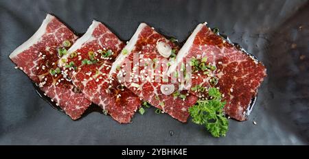 Wagyu Australia, ein köstliches Rindfleisch mit sehr hoher Marmorierung, serviert auf schwarzem Teller mit Sauce und gehackter Schalotte. Draufsicht Stockfoto