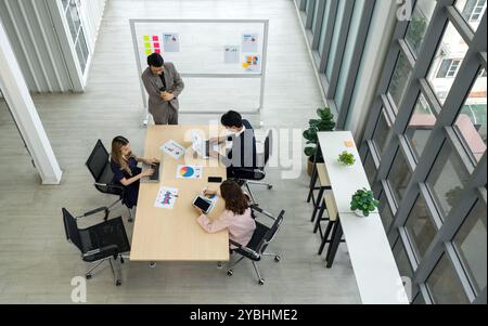 In einem Besprechungsraum versammeln sich Geschäftsleute, die an einem großen Konferenztisch Ideen diskutieren und austauschen. Stockfoto