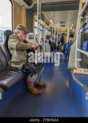 Edinburgh, Schottland, 10. Mai 2024: Ein Schotte, gekleidet in traditionellen Kilts und Sporrans, pendelt in einer Straßenbahn in der Princess Street. Stockfoto