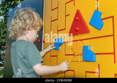 Der kleine Junge erkundet den Außenbus auf dem Spielplatz Stockfoto