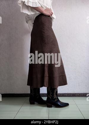 Retro-Outfit, Edler Vintage-Rock Aus Echtem Wildleder, Cowboy-Stiefel, Weiße Böhmische Bluse, Vorderansicht, Outfit-Details, anonyme Frau, Brown A Line Boho Patchwork Midi Rock, Kaffeerock Stockfoto