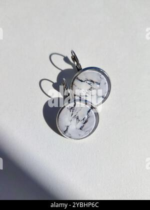 Handgemachte Harz Runde Marmor Textur Stein Ohrringe transparente Oberfläche weißer Schatten Hintergrund. Leverback Haken, sichere Kleidung, naturinspirierter Schmuck Stockfoto