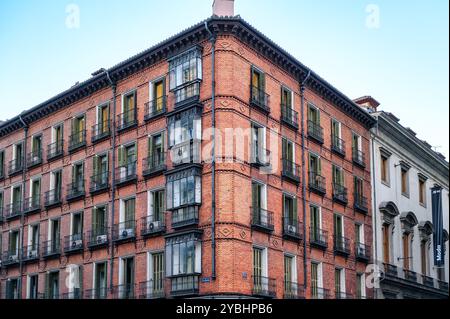 Madrid, Spanien - 8. Februar 2023: Altes Backsteinmauergebäude mit Details von geschlossenen Balkonen. Stockfoto