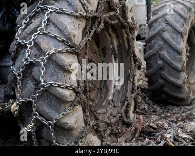 Ein Traktor Reifen mit Ketten für Schlamm. Die Details der Räder und Reifen des landwirtschaftlichen Fahrzeugs. Ausgestattet mit Reifenketten zum Einfahren von Schlamm Stockfoto