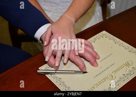 Bild der Braut und des Bräutigams Hände beim Unterschreiben der Hochzeitsurkunde Stockfoto