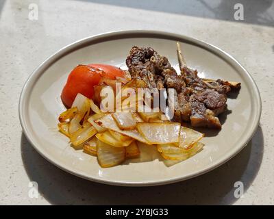 Seitenansicht des gegrillten Lammes mit Zwiebeln und Tomaten auf dem Teller zum Essen Stockfoto