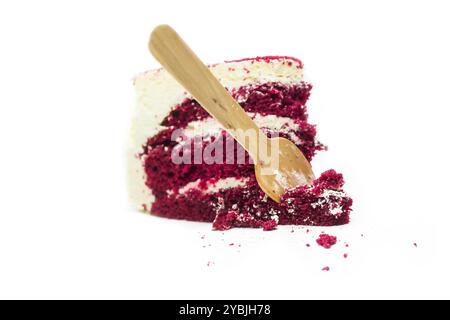 Scheibe roter Samtkuchen mit cremigen Schichten mit Holzlöffel auf weißem Hintergrund. Stockfoto