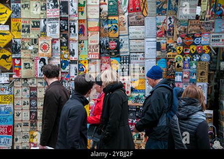 Touristen vor einem Verkaufsstand, an dem auf dem Portobello Road Market Sammlerstücke aus Metall verkauft werden. London Stockfoto