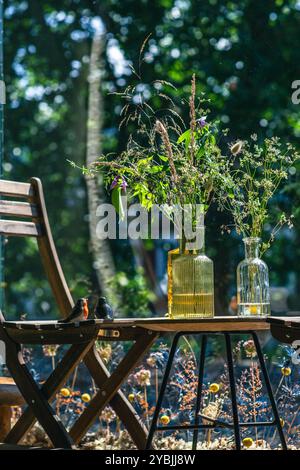 Gartenblumen in farbigen Glasflaschen Stockfoto