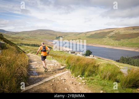Yorkshire Dales, Großbritannien - 14. September 2024. Männlicher Trailläufer läuft bergab in Richtung Scar House Reservoir, Nidderdale, North Yorkshire, Großbritannien Stockfoto