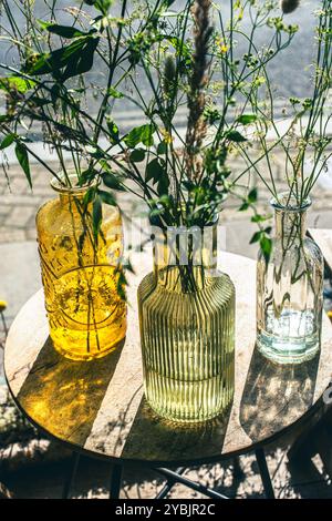 Gartenblumen in farbigen Glasflaschen Stockfoto