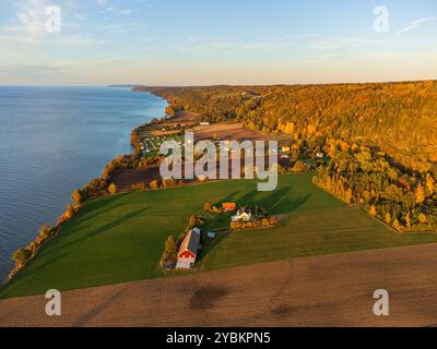 Typisch schwedische Landschaft in herbstlichen Farben, bei Sonnenuntergang, aus der Luft, in der Nähe des Sees Vättern. Wunderschönes Herbstlaub. Weit entfernte Windmühlen. Stockfoto