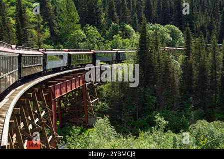 Ein Zug umrundet eine gekrümmte Brücke über eine Schlucht in der Nähe von Skagway, Alaska. Stockfoto