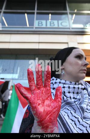 Birmingham, England, Großbritannien. Oktober 2024. Ein Demonstrant hält rote Hände hoch, die das Blut an den Händen der Medien während der Demonstration zeigen. Demonstranten versammeln sich, um gegen die BBC und die Western Media zu marschieren. Die Demonstranten argumentieren, dass die Medien nicht einmal überliefert wurden, wenn sie Nachrichten aus dem Nahen Osten berichteten, was die Ereignisse in Gaza und im Libanon zugunsten des israelischen Regimes verzerrt. Sie glauben, dass dieses Verhalten diese Organisationen zu Komplizen an dem, was sie als Völkermord am palästinensischen Volk betrachten. Stockfoto