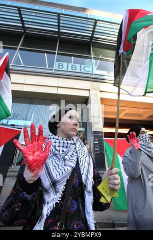 Birmingham, England, Großbritannien. Oktober 2024. Ein Demonstrant hält rote Hände hoch, die das Blut an den Händen der Medien während der Demonstration zeigen. Demonstranten versammeln sich, um gegen die BBC und die Western Media zu marschieren. Die Demonstranten argumentieren, dass die Medien nicht einmal überliefert wurden, wenn sie Nachrichten aus dem Nahen Osten berichteten, was die Ereignisse in Gaza und im Libanon zugunsten des israelischen Regimes verzerrt. Sie glauben, dass dieses Verhalten diese Organisationen zu Komplizen an dem, was sie als Völkermord am palästinensischen Volk betrachten. Stockfoto