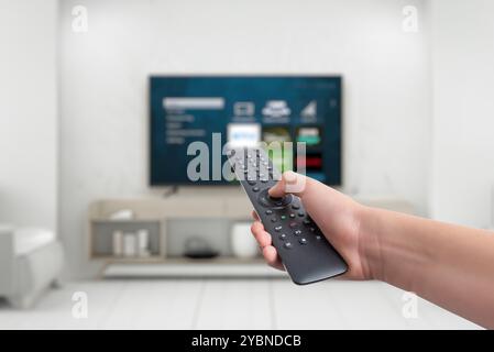 Die Hand hält eine Fernbedienung für einen Smart TV mit App-Tasten für Streaming-Dienste. Konzept der vielseitigen Unterhaltung, die den Funktionsumfang vorstellt Stockfoto