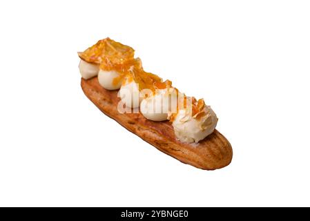 Süße Desserteclairs oder Profiterolen mit Schokoladenfüllung, bedeckt mit Sahne und getrockneten Orangen auf weißem Hintergrund Stockfoto