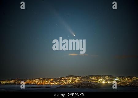 Der Komet ist wie eine riesige Taschenlampe über dem kleinen Dorf. Stockfoto