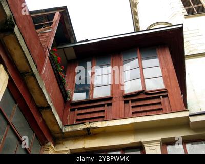 Die Holzattika sind im Landhausstil eingerichtet und verfügen über große Fenster und einen mit Blumen geschmückten Balkon in einem historischen Innenhof von Lemberg. Stockfoto