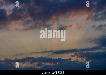 Der Dämmerungshimmel zeigt eine faszinierende Mischung von Farben, während sich Wolken mit Sonnenstrahlen vermischen und während der Zeit eine ruhige Atmosphäre über die Landschaft zaubern Stockfoto