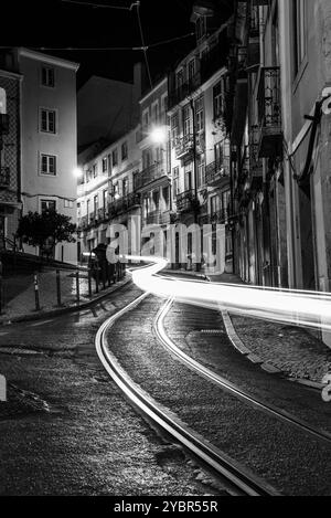 Scheinwerferlinien von Autos, die auf der Straße Poiais de Sao Bento im Zentrum von Lissabon, Portugal, vorbeifahren Stockfoto