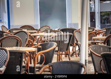 Leerer Sitzbereich im Freien in einem Café mit Korbstühlen und Tischen, die Gastfreundschaft und Catering-Service bieten. Stockfoto