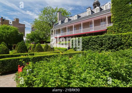 Touristen in den geteilten Pflanzen- und Gemüsegärten des Gouverneurs hinter Chateau Ramezay, teilweise bedeckt mit Kletterpflanzen im Frühjahr. Stockfoto