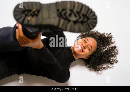 Junge Schwarze Frau Tritt Stiefel Nach Oben Studio Boden Weißer Hintergrund Lächelnd Stockfoto
