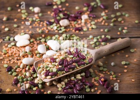 Gemischte Samenleguminosen in einem Löffel auf einem alten Holztisch Stockfoto