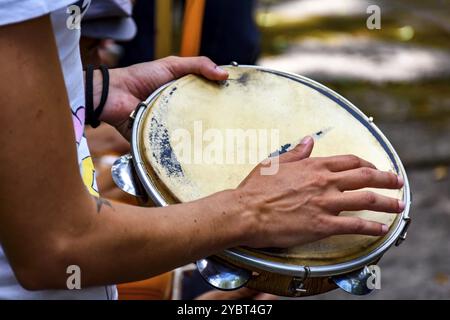 Detail eines Musikers, der Tamburin spielt, während einer Samba-Vorstellung auf dem Karneval in den Straßen Brasiliens Stockfoto