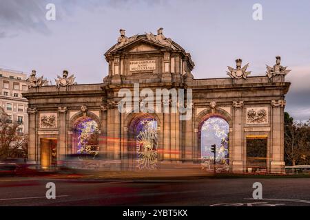 Puerta de Alcala Denkmal in Madrid während der Weihnachtszeit bei Sonnenuntergang. Langzeitbelichtung mit Ampelspuren Stockfoto