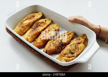 Weibliche Hand hält ein Tablett mit Torrijas, ein typisch spanisches süßes gebratenes Brot in Scheiben, das in Eier und Milch getränkt ist, auf weißem Hintergrund. Tradition Stockfoto