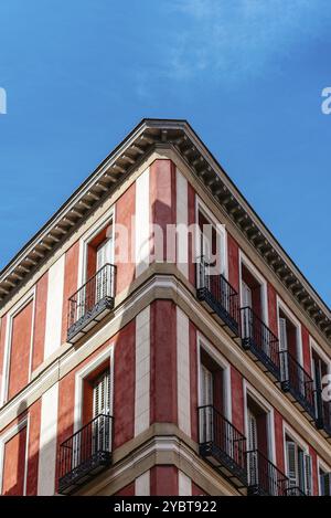 Niedriger Winkel Blick auf die Ecke eines alten, kürzlich renovierten Wohnhauses gegen blauen Himmel. Vertikale Aufnahme, Symmetrie Stockfoto