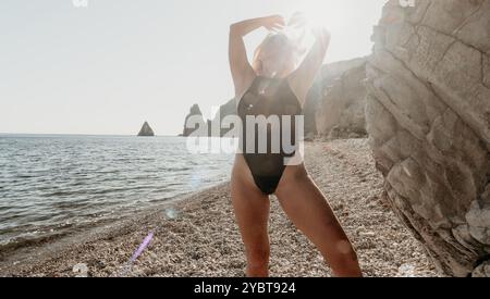 Frau im schwarzen Badeanzug posiert am Strand Stockfoto