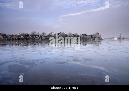 Blick auf das niederländische Dorf Zaandijk über den teilweise gefrorenen Fluss Zaan Stockfoto