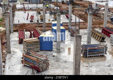 Baustelle mit Stahlbetonstützen und verzinkten Stahlstreben Und Holzbaukonstruktionen gestapelt bereit für den Bau von A Stockfoto