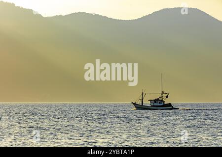 Fischtrawler segeln vor den Bergen von Ilhabela während Sonnenuntergang Stockfoto