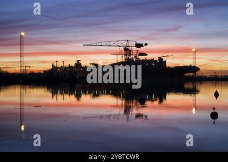 Spektakulärer Sonnenaufgang über einer Werft am Ufer des niederländischen Flusses merwede Stockfoto