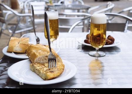 Eiskalte Biere, die auf der Terrasse in Gläser gegossen werden, mit Tapas, spanischem Omelett und Chicken Wings. Platz für Kopie Stockfoto