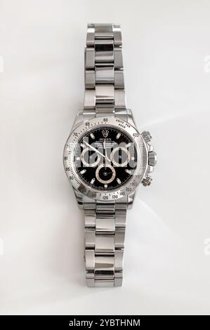 Blick von oben auf die elegante Daytona Cosmograph Rolex-Uhr aus Stahl mit schwarzem Zifferblatt und Armband aus Oystersteel auf weißer Oberfläche Stockfoto