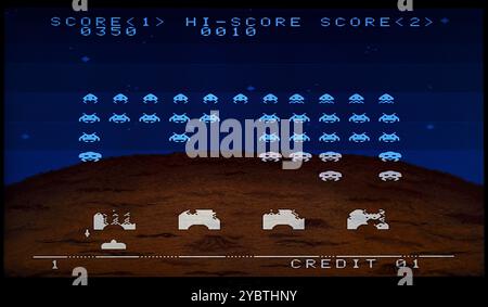 Das Retro Arcade Space Invaders Spiel läuft und zeigt gepixelte Alien-Eindringlinge, die in einer gepixelten Landschaft absteigen Stockfoto