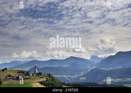 Blick auf die St. Nikolaus Kirche in Mittelberg in der Gemeinde Ritten in Südtirol mit den Dolomitengipfeln im Hintergrund Stockfoto