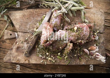 Zubereitung mit gehackten aromatischen mediterranen Kräutern aus rohen Kaninchenportionen Stockfoto